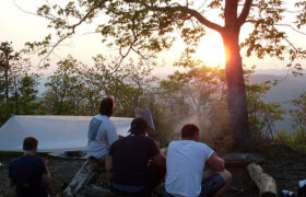 men camping at sunset